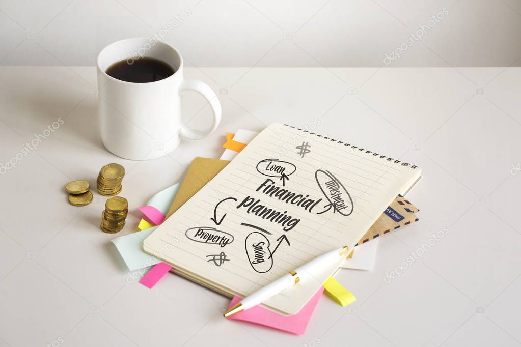 Financial planning table top with notebook and cup of coffee table top shot.