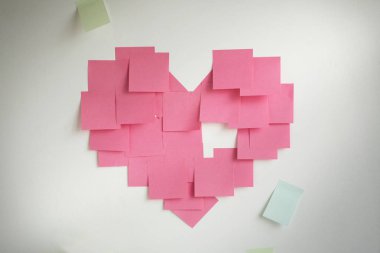 Boş pembe yapışkan notlar duvarda bir kalp şeklinde yapıştırılmış. 