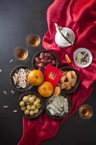 Flat lay Chinese New Year food and drink group of objects still life on red satin and black background. Text appear in image :Prosperity.