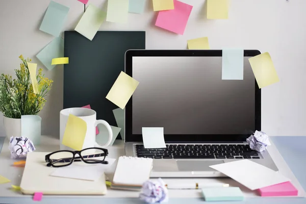 Messy office table top with text space laptop screen.