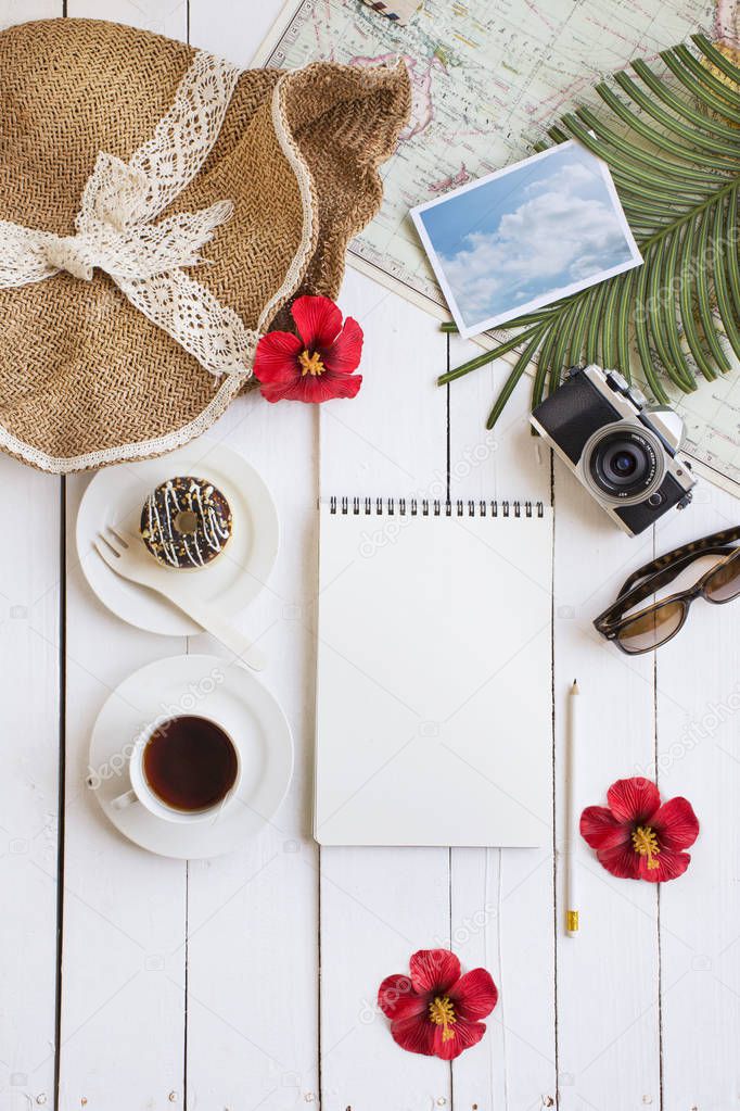 Summer travel vacation planning and objects on white outdoor cafe table top.