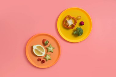 Pembe arka planda renkli dilimlenmiş meyve ve sebze.