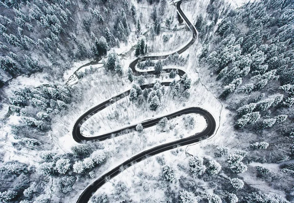 Snowy road in the forest. Extreme winding road high up in the mountains