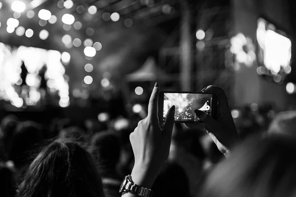Recording a concert on a mobile phone from the crowd, black and white version