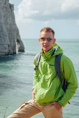 Gökyüzü ve deniz manzara arka planda genç bir başarılı adamın portresi. Yeşil ceket gözlüklü sarışın