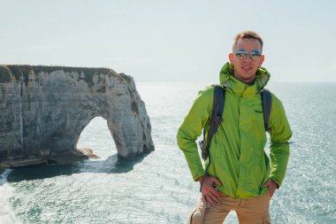 Gökyüzü ve deniz manzara arka planda genç bir başarılı adamın portresi. Yeşil ceket gözlüklü sarışın