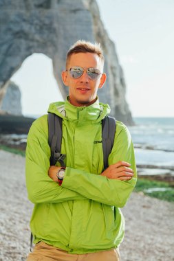 Gökyüzü ve deniz manzara arka planda genç bir başarılı adamın portresi. Yeşil ceket gözlüklü sarışın