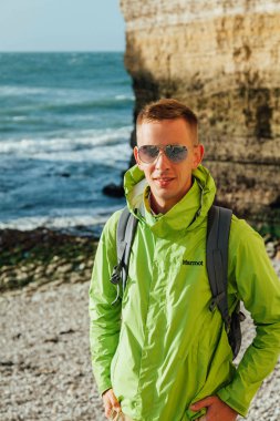 Gökyüzü ve deniz manzara arka planda genç bir başarılı adamın portresi. Yeşil ceket gözlüklü sarışın