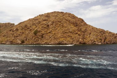 Bir görünüm bir kayalık ada ve Yunanistan Ege Denizi'nde geçirerek bir motorlu tekne