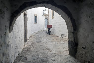 Arch ve ahşap windows ile dar bir sokak ve kapı beyaz duvar taş mimarisi, Island Patmos, Yunanistan ile bir görünüm