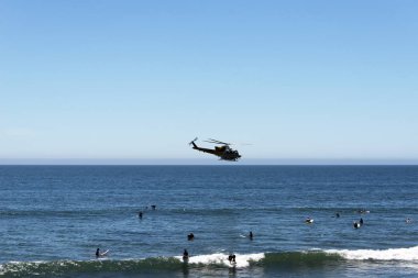 Malibu beach ve sörfçü California yaz aylarında üzerinde uçan bir yangın helikopteri bir görünümünü