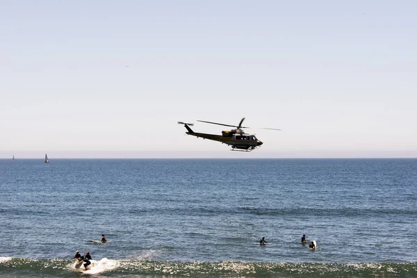 Malibu beach ve sörfçü California yaz aylarında üzerinde uçan bir yangın helikopteri bir görünümünü