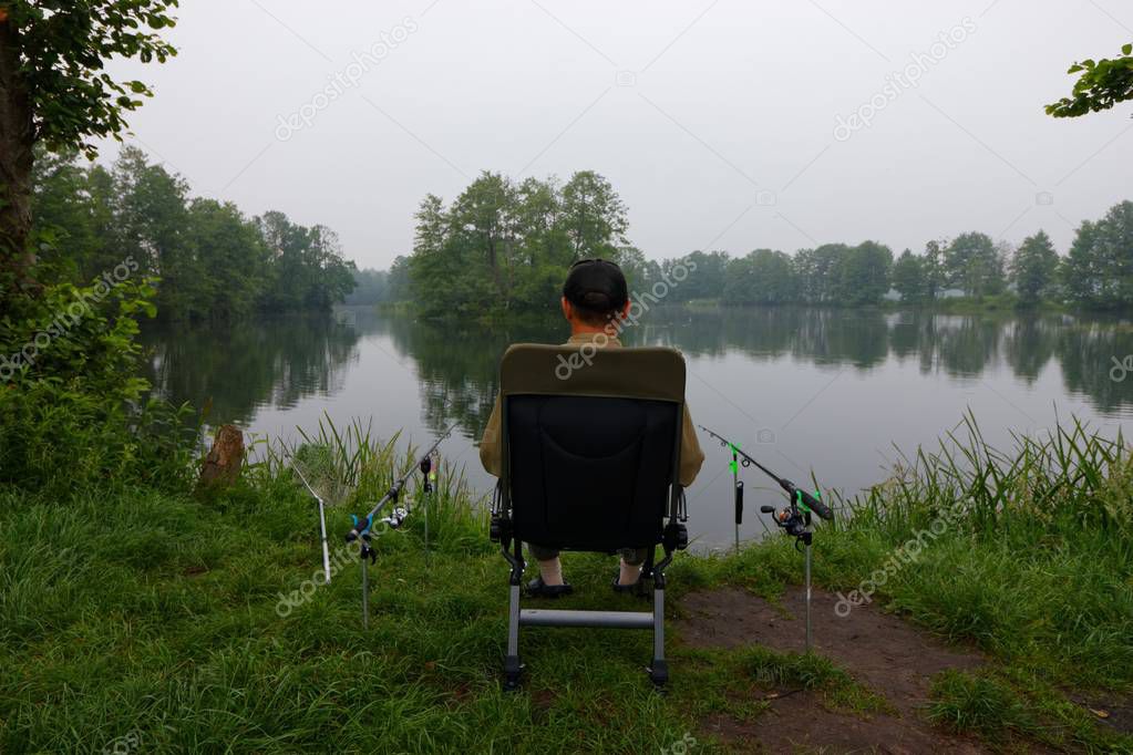 Fisherman sitting on the chair and fishing during cloudy day