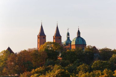 Cathedral towers amidst autumnal trees, Tumskie Hill in Plock, Poland clipart