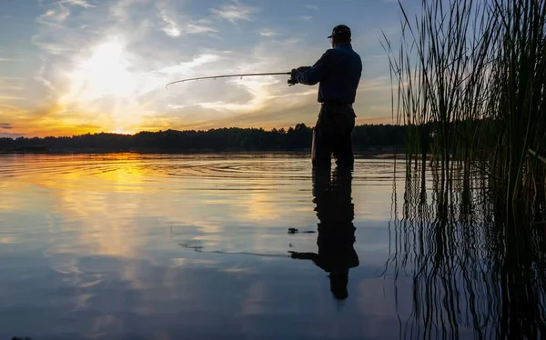 Balıkçı gün batımında gölde balık yakalıyor.