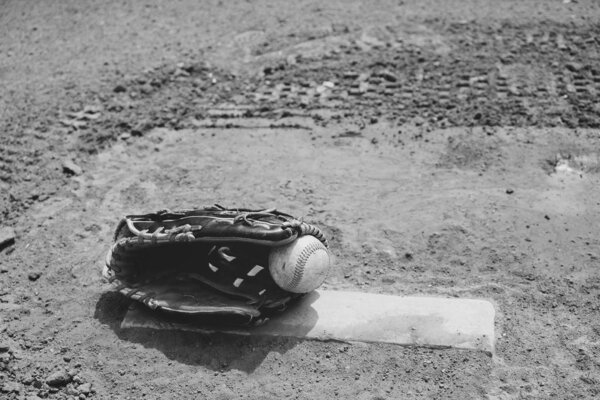 Old baseball lays in players glove on pitchers mound of field for game.