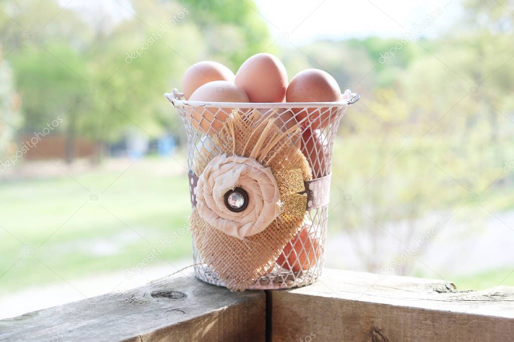 Fresh farm eggs sit outdoors in rustic basket.