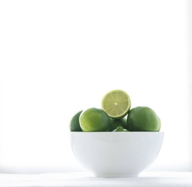 Beyaz bir kase içinde bazı limes ile beyaz bir arka plan üzerinde izole kapatın. Limes biridir iki halfs kesilerek. 
