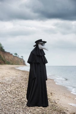 Seaside Plague Doktor. Açık öğe, dikey, arka planda dramatik gökyüzü.