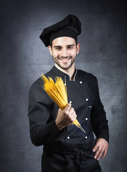 Onun Eli Gri Arka Planda Spagetti Ile Siyah Üniforma Giyen — Stok fotoğraf