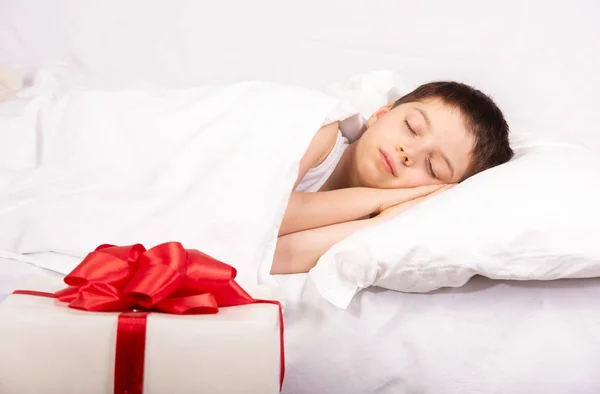 Milý chlapeček spí ve svém domě s dárkem — Stock fotografie