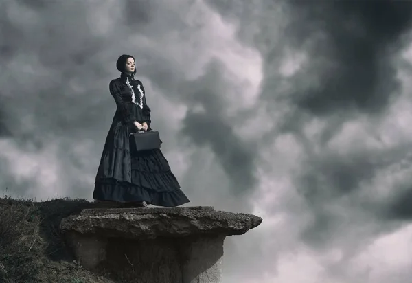 Outdoors portrait of a victorian lady in black standing on the c — Stock Photo, Image