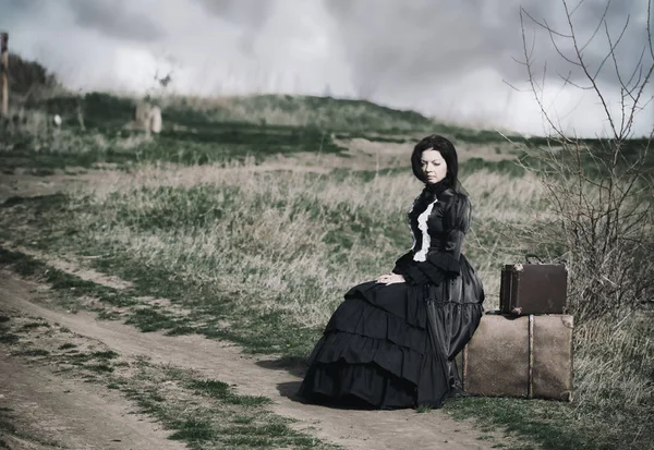 Outdoors portrait of a victorian lady in black sitting alone on — Stock Photo, Image
