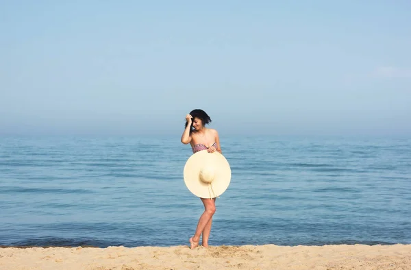 青い水で夏に楽しいビーチを楽しむ幸せな女性 ビーチサンハットを着て旅行で幸せな美しいビキニモデル — ストック写真
