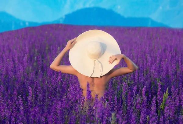 紫色の野原に立つ大きな帽子をかぶったかわいい女の子 — ストック写真