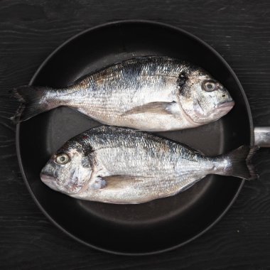 Koyu bir arka plan üzerinde bir tavada taze fikse dorado