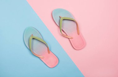 Pembe ve mavi pastel arka planda şık plaj parmak arası terlikler, üst görünüm. Kopyalama alanı ile yaz konsepti.