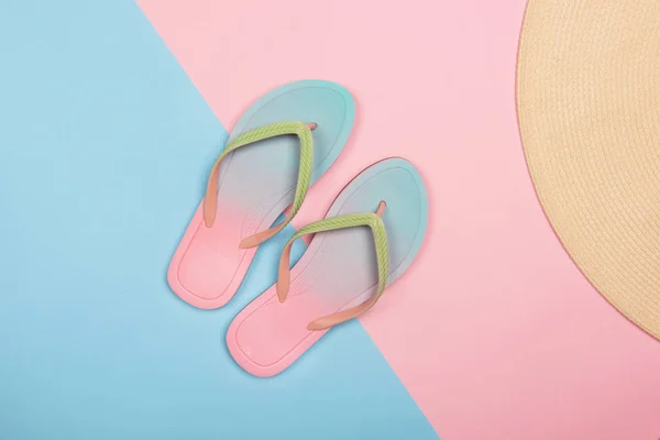 Stijlvolle strand slippers en zonnehoed op roze en blauwe pastel achtergrond, Top uitzicht. Zomer concept met Kopieer ruimte. — Stockfoto