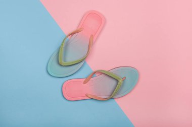 Pembe ve mavi pastel arka planda şık plaj parmak arası terlikler, üst görünüm. Kopyalama alanı ile yaz konsepti.