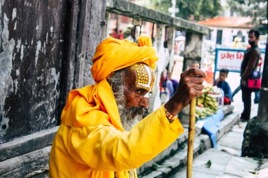 Katmandu Nepal 1 Eylül 2018 bir Sadhu ile boya portresi nokta Kathmandu Durbar Meydanı'nda sabah oturan yüz ve sarı giysiler