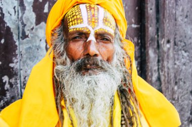 Katmandu Nepal 1 Eylül 2018 bir Sadhu ile boya portresi nokta Kathmandu Durbar Meydanı'nda sabah oturan yüz ve sarı giysiler