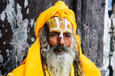 Katmandu Nepal 1 Eylül 2018 bir Sadhu ile boya portresi nokta Kathmandu Durbar Meydanı'nda sabah oturan yüz ve sarı giysiler