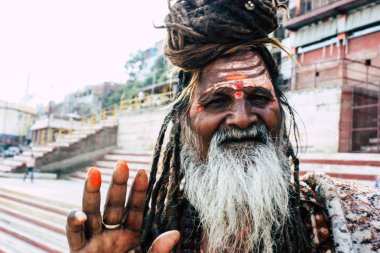 Varanasi Hindistan 8 Kasım 2018 oturan ve yem um sigara bilinmeyen kutsal Sadhu görünümünü ön Ganj Nehri öğleden sonra