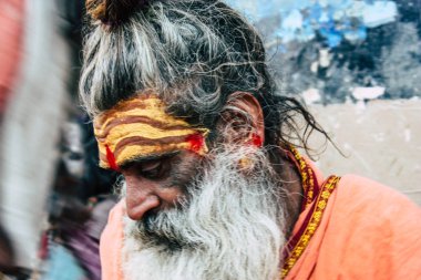 Varanasi Hindistan 8 Kasım 2018 oturan ve yem um sigara bilinmeyen kutsal Sadhu görünümünü ön Ganj Nehri öğleden sonra