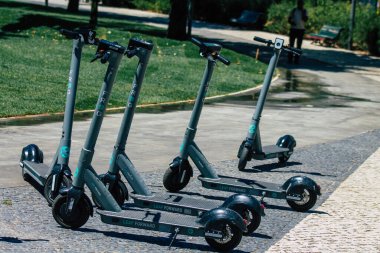 Lizbon Portekiz 25 Temmuz 2020 'de Lizbon sokaklarında park etmiş küçük bir iç yanmalı motor ve merkezde büyük bir güverte ile çalışan elektrikli scooter görüntüsü.