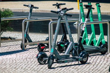 Lizbon Portekiz 25 Temmuz 2020 'de Lizbon sokaklarında park etmiş küçük bir iç yanmalı motor ve merkezde büyük bir güverte ile çalışan elektrikli scooter görüntüsü.