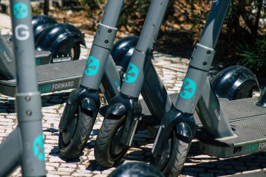 Lizbon Portekiz 25 Temmuz 2020 'de Lizbon sokaklarında park etmiş küçük bir iç yanmalı motor ve merkezde büyük bir güverte ile çalışan elektrikli scooter görüntüsü.