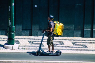 Lizbon Portekiz 25 Temmuz 2020 Lizbon sokaklarında elektrikli scooterla dolaşan, küçük bir iç yanmalı motorla çalışan ve merkezde bir güverte bulunan kimliği belirsiz insanların görüntüsü.