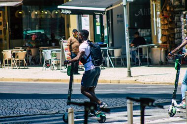 Lizbon Portekiz 28 Temmuz 2020 Lizbon sokaklarında elektrikli scooterla gezen kimliği belirsiz insanların görüntüsü, küçük bir iç yanmalı motorlar ve merkezde bir güverte ile çalışıyor.