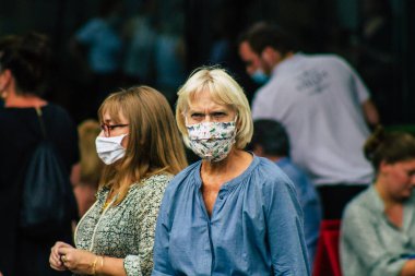 Fransa 'yı 15 Ağustos 2020' de, Fransa 'nın Grand Est bölgesindeki bir şehir olan Reims sokaklarında yürüyen koronavirüsten kendilerini korumak için maske takan kimliği belirsiz yayalara bakıyor.