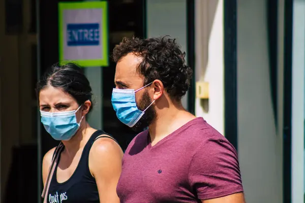 Fransa 'yı 15 Ağustos 2020' de, Fransa 'nın Grand Est bölgesindeki bir şehir olan Reims sokaklarında yürüyen koronavirüsten kendilerini korumak için maske takan kimliği belirsiz yayalara bakıyor.