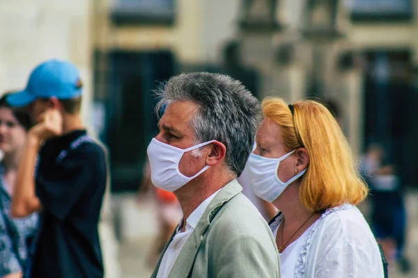 Fransa 'yı 15 Ağustos 2020' de, Fransa 'nın Grand Est bölgesindeki bir şehir olan Reims sokaklarında yürüyen koronavirüsten kendilerini korumak için maske takan kimliği belirsiz yayalara bakıyor.