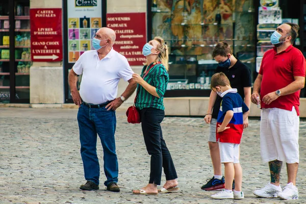Fransa 'yı 15 Ağustos 2020' de, Fransa 'nın Grand Est bölgesindeki bir şehir olan Reims sokaklarında yürüyen koronavirüsten kendilerini korumak için maske takan kimliği belirsiz yayalara bakıyor.