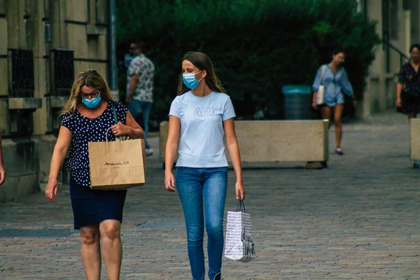 Fransa 'yı 15 Ağustos 2020' de, Fransa 'nın Grand Est bölgesindeki bir şehir olan Reims sokaklarında yürüyen koronavirüsten kendilerini korumak için maske takan kimliği belirsiz yayalara bakıyor.