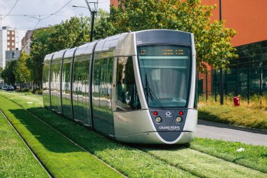 Fransa 'yı 15 Ağustos 2020' de, Fransa 'nın Grand Est bölgesindeki bir şehir olan Reims toplu taşıma sisteminin bir parçası olan caddelerden geçen yolculara yönelik modern bir elektrikli tramvaya bakıyor.