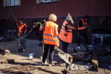 Kharkiv, Ukrayna, 16 Eylül 2025 Temizlik işçileri, Rus Şahin İHA 'sının bir binaya çarptığı sokakta karşılık veriyor. Hasar büyüktü ve bina alev aldı..